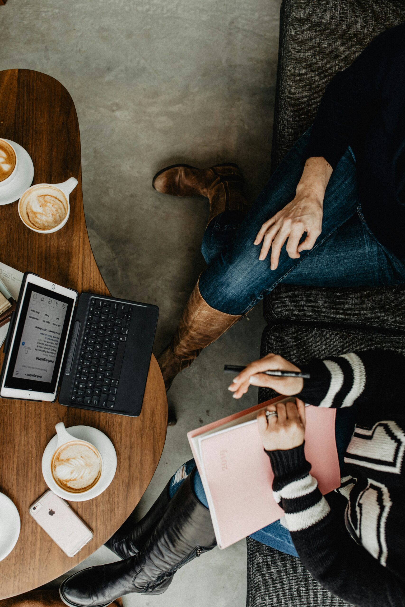 rachel-mcdermott-a_GgW9FzcSo-unsplash - Indigo Valley Overhead view of two people working at a cafe table with a tablet and keyboard, a notebook and several lattes.