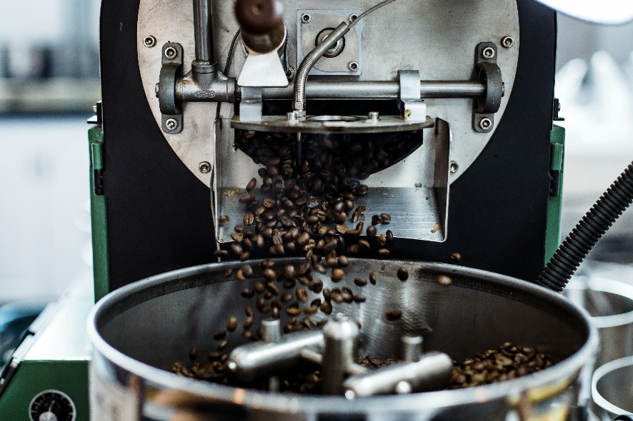 Screenshot 2026-08-11 at 153138 - Indigo Valley Freshly roasted coffee beans pouring from the drum of a commercial coffee roaster into the metal cooling tray below.